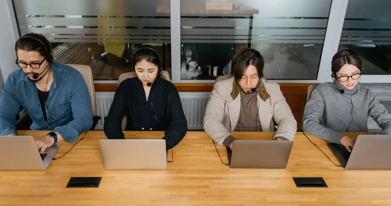 Team of customer service representatives wearing headsets while working on laptops